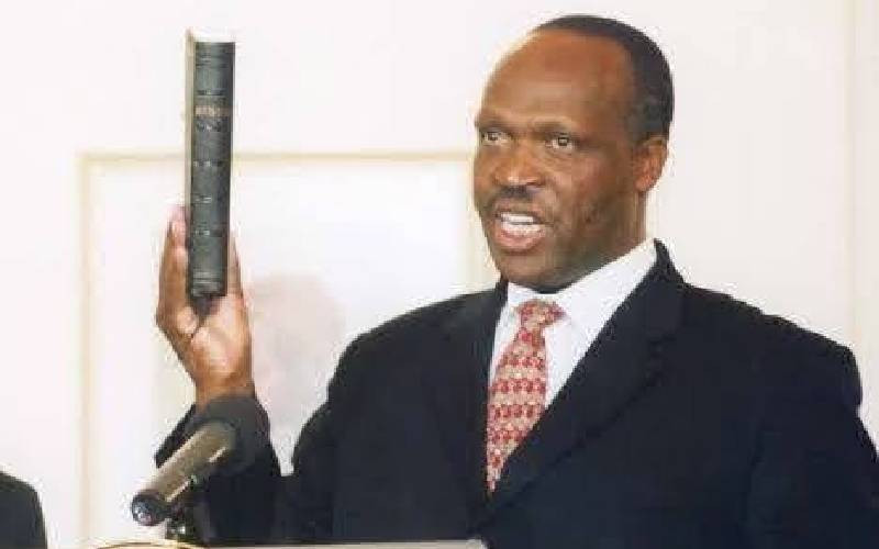 A man in a suit holding a book beside a microphone